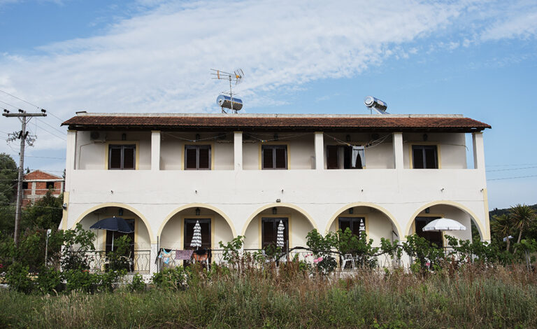 Exterior of Villa Maria Perivoli, a two-storey building with an arched ground-floor terrace in Corfu
