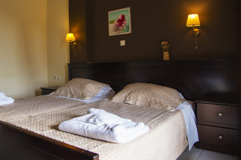 Twin beds with bedside reading lamps in a studio at Villa Maria Perivoli